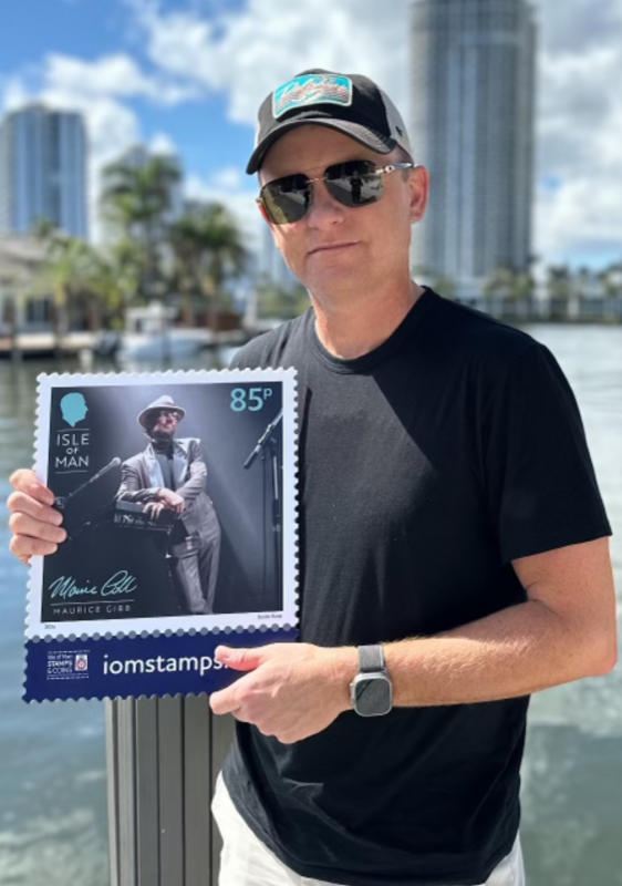 Adam Gibbb with Maurice Gibb CBE Stamp Board in Miami